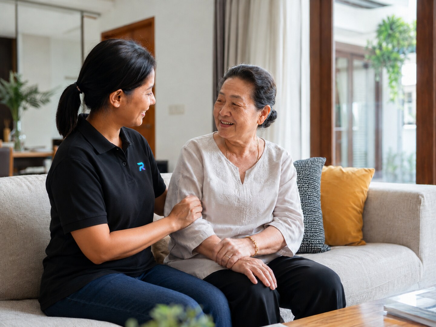 Ready Maid helper in a black polo supporting an elderly Malaysian Chinese woman at home